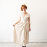 A model wearing a mid-weight linen reversible wrap dress with a V-neckline and sleevless, in black color.